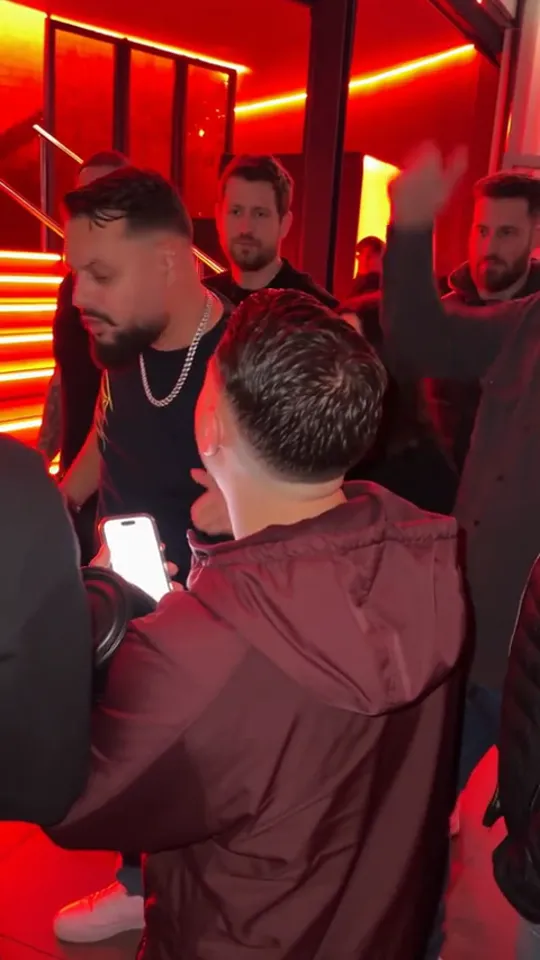 The same man turning sideways with one hand thrown up while the crowd behind him raises their hands