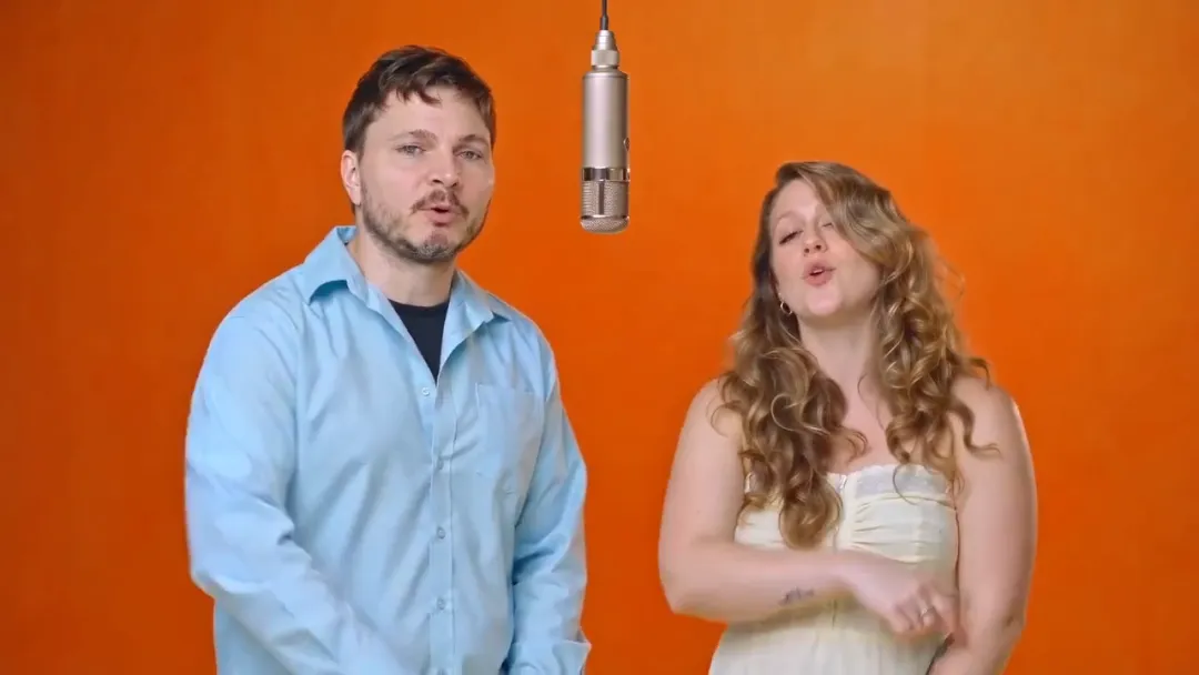Closing beat of the hotel lobby AI video: each person strikes their own pose with the microphone centered between them