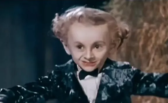 The AI little man in a hay barn spreads his arms wide with a sly grin