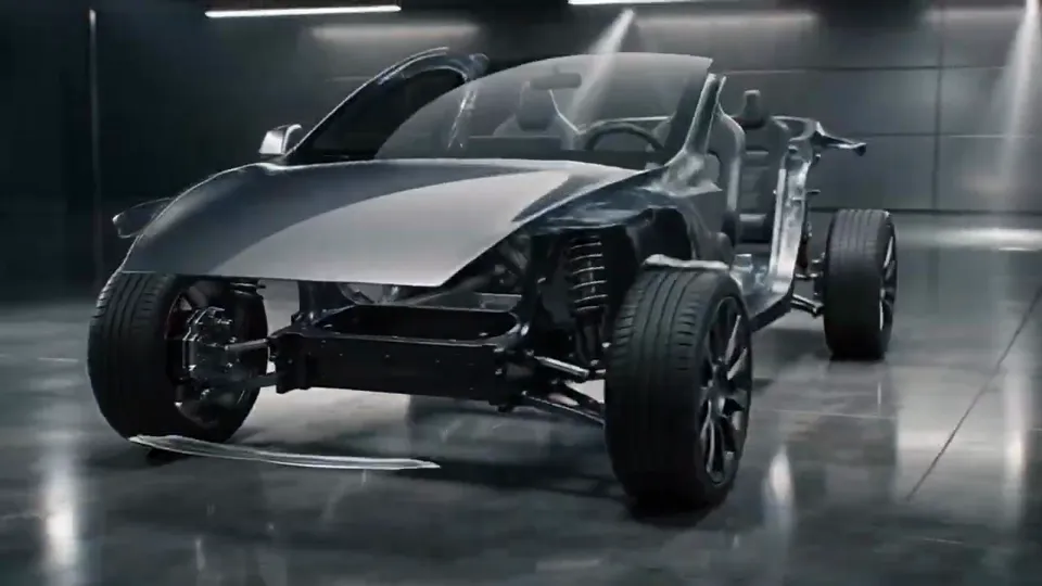 A chassis with wheels and seats in place while body panels close in around it in a studio