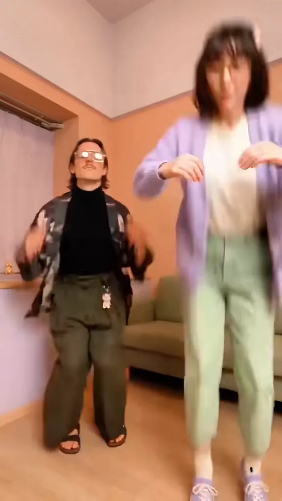 The same living room later, the friend who had arms crossed starts dancing too